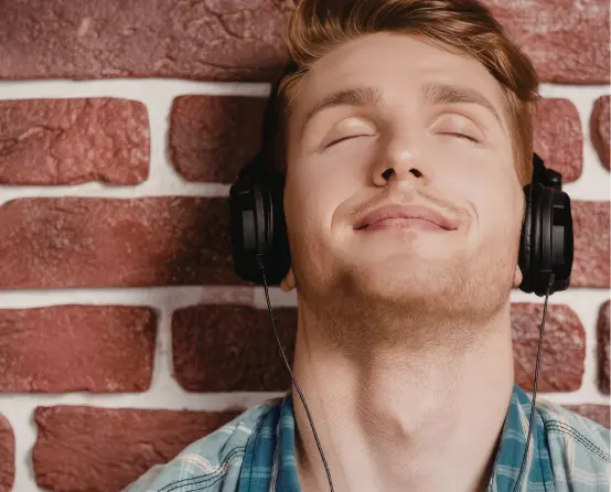 A young person listening to music through headphones, eyes closed